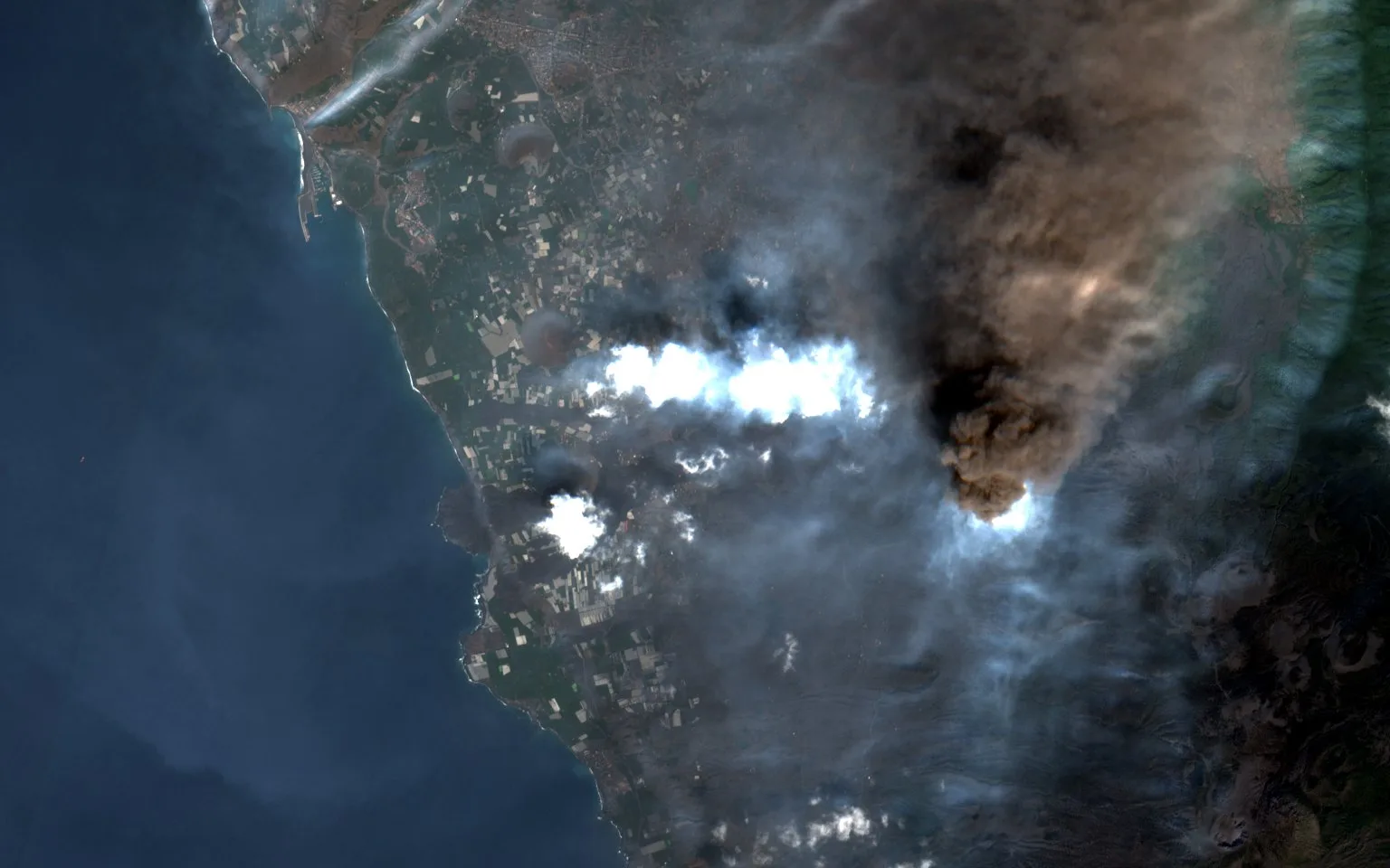 The same coast in mid October, much of it under the eruption plume, with the lava flows widening below