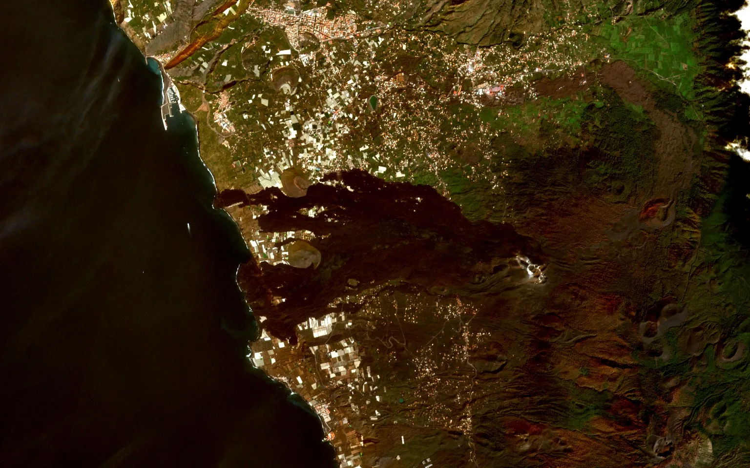 The same coast after the eruption, with a broad black lava field crossing the land from the hills to two new deltas in the sea, and the plantations left on either side